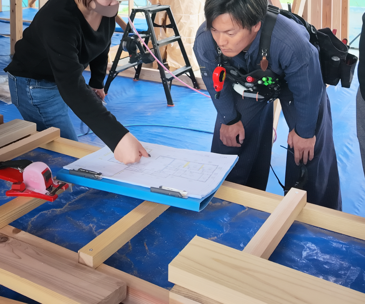 現場で図面を確認する設計士と職人